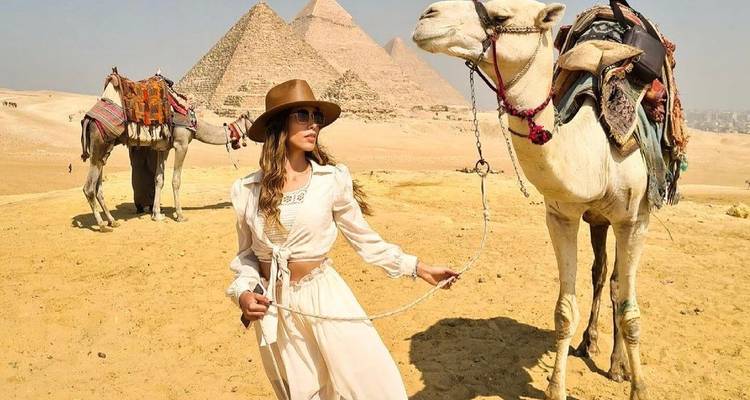 Person with a camel in front of the Pyramids of Giza.