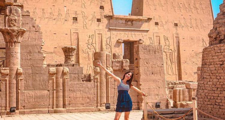 Person posing in front of ancient temple walls with hieroglyphs.