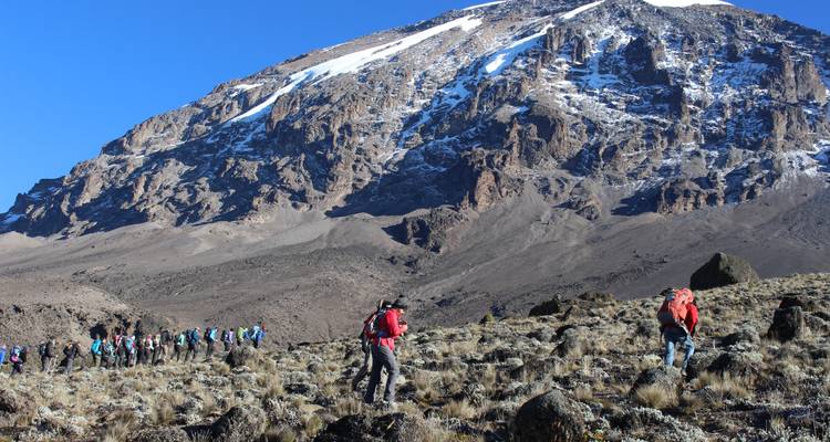 Groupe de randonneurs s'approchant d'une montagne enneigée.