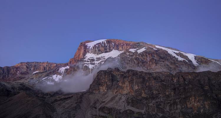 Un sommet de montagne enneigé émergeant de la brume.