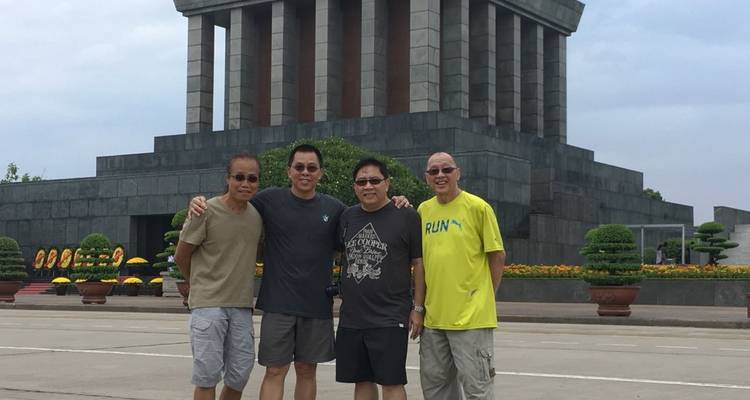 Vier Menschen stehen vor einem großen Denkmal in einem offenen Bereich.