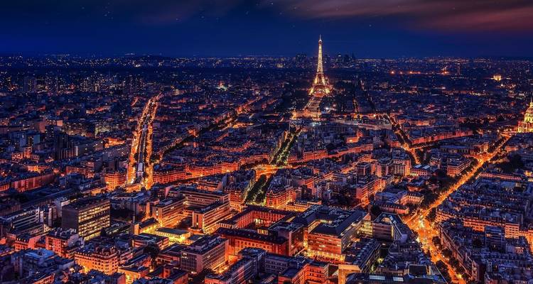 Vue aérienne nocturne des lumières de la ville avec la tour Eiffel.