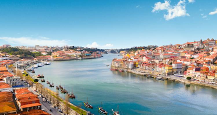 Vue aérienne générale de Porto et du fleuve Douro bordés de bâtiments anciens aux couleurs vives.