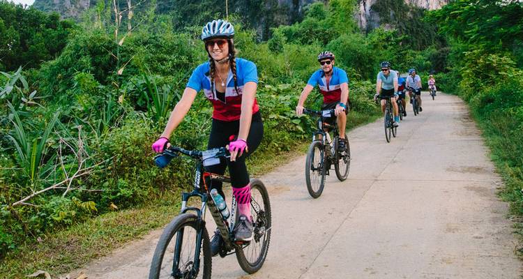 Gruppe von Menschen, die auf einem Weg in einem bewaldeten Gebiet Fahrrad fahren.