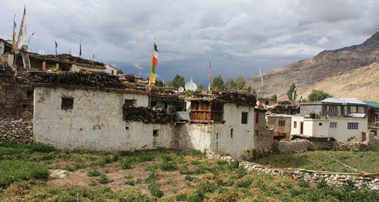 Pueblo con casas tradicionales de piedra y banderas coloridas contra cielos nublados.