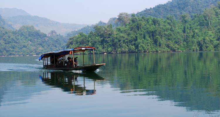 Un barco navegando en un lago tranquilo con un bosque de fondo.