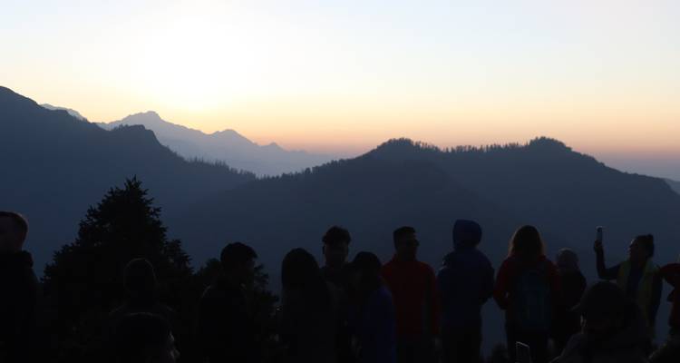 Silhouettes de personnes avec un lever de soleil en montagne en arrière-plan.