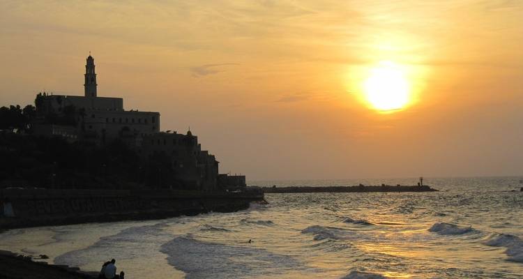 Sonnenuntergangsblick auf eine Küstenstadt mit der Silhouette von Gebäuden.