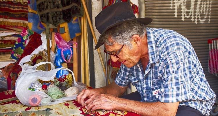 Person, die an einem Marktstand mit bunten Stoffen bastelt.