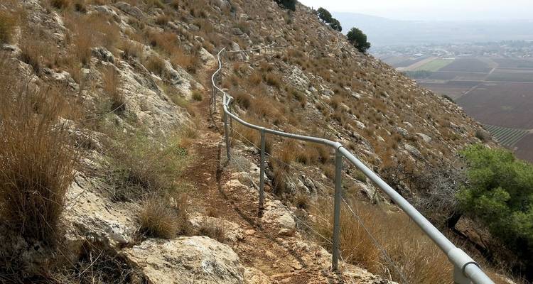 Schmaler Wanderweg an einem felsigen Hang.
