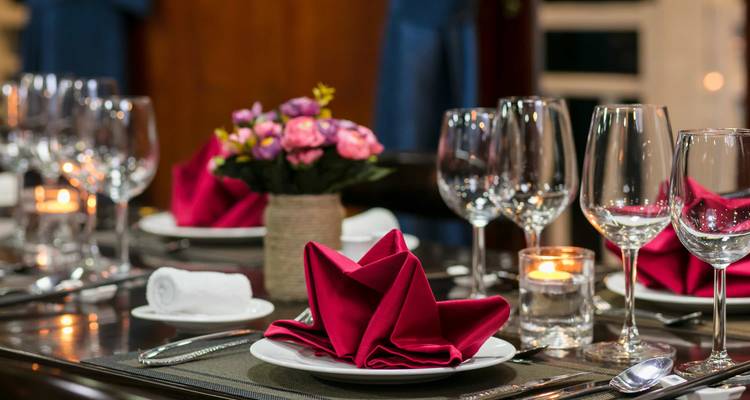 Close-up of a beautifully set dining table with folded napkins and glasses.