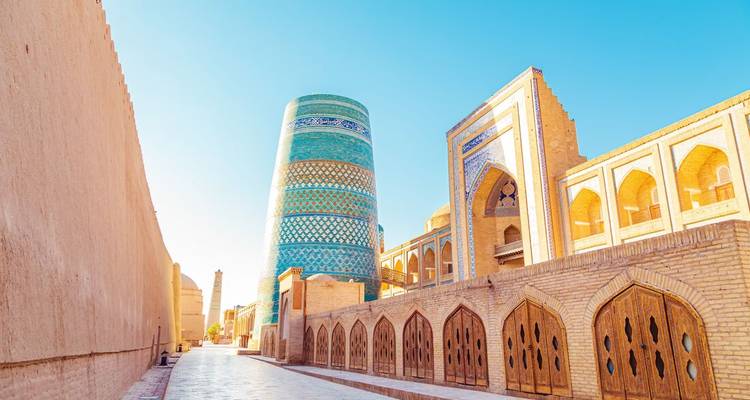 Colorful decorated minaret and historic buildings under a blue sky.