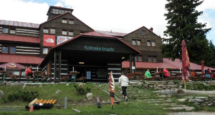 Kolinska Bouda mit Menschen, die draußen in einer Berglandschaft sitzen.