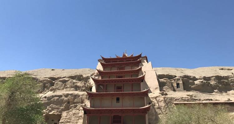 Pagode intégrée dans des formations rocheuses sous un ciel bleu.