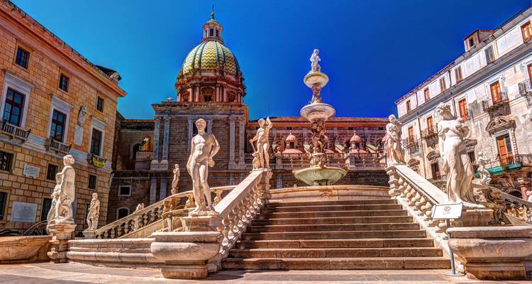 Image vibrante de la Fontana Pretoria de Palerme avec des statues en marbre et un dôme baroque sous un ciel bleu profond.