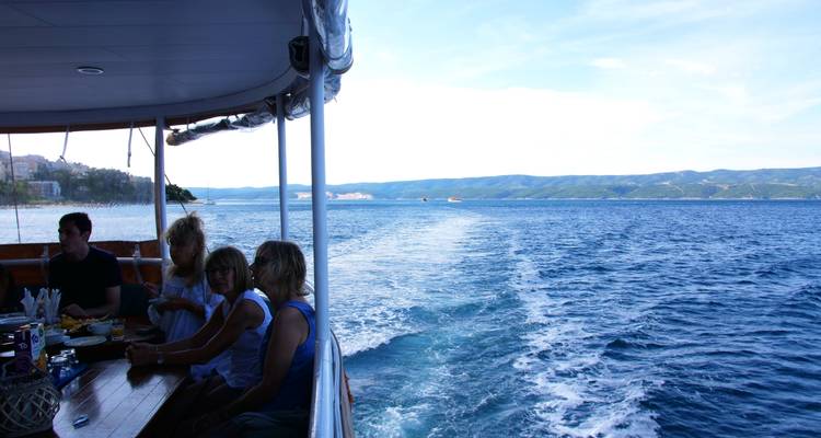 Personas sentadas en un barco disfrutando de la vista del mar.