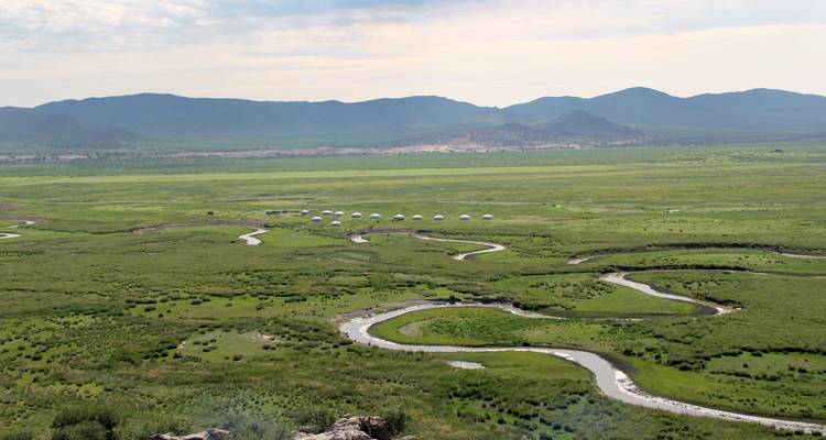 Vue panoramique sur une vallée avec des rivières sinueuses et des yourtes au loin.