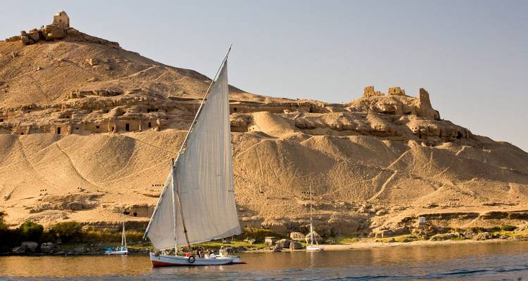 Sailboat on the Nile River with ancient ruins on the hill.