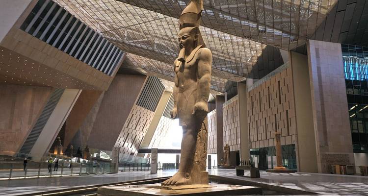 A large ancient statue inside a modern architectural building, similar to another image.