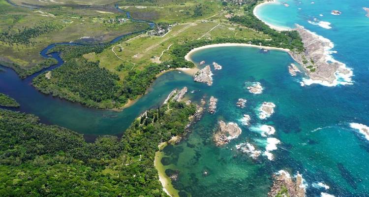 Una vista aérea de un paisaje costero exuberante con un río que se encuentra con el océano.