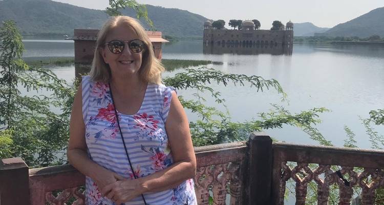 Turista posando con un palacio pintoresco del lago en el fondo.