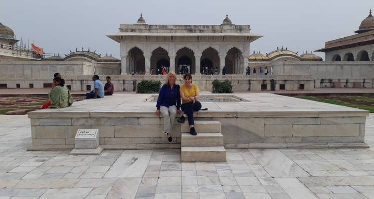 Turistas sentados en un monumento de mármol.