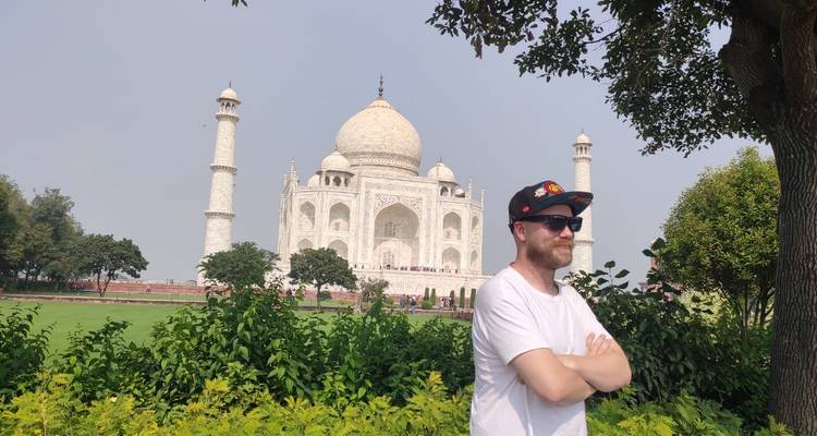 Homme posant avec le Taj Mahal en arrière-plan.
