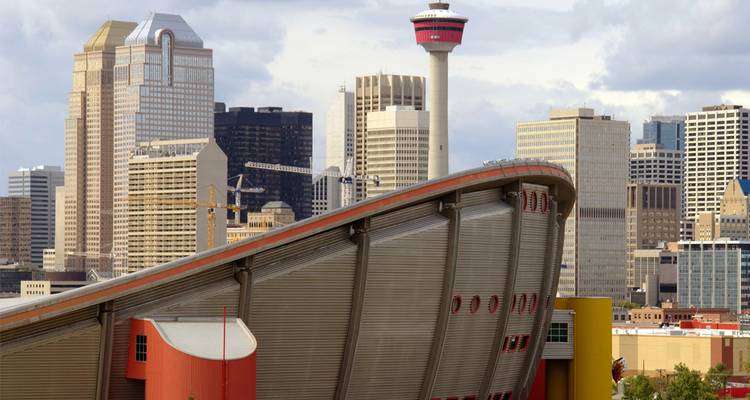 El horizonte de Calgary con el icónico Saddledome y la Torre de Calgary se alzan majestuosos bajo un cielo parcialmente nublado.