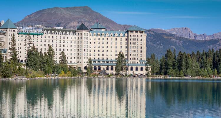 El majestuoso Chateau Lake Louise se encuentra en la orilla del lago turquesa, reflejándose perfectamente contra los picos que lo rodean.