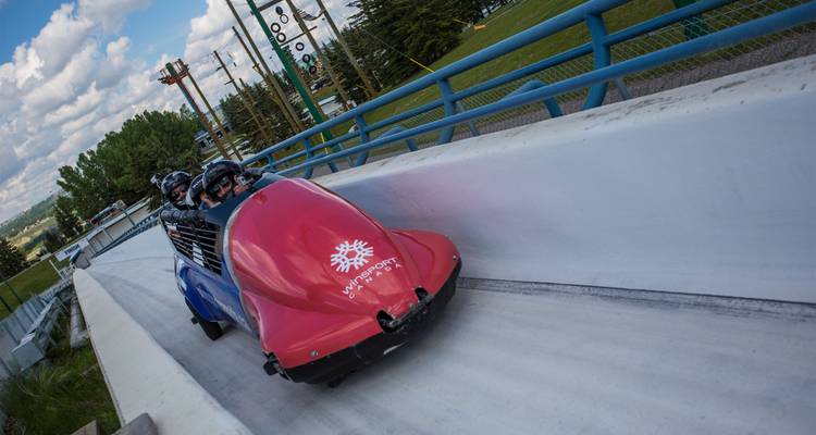Los buscadores de adrenalina descienden a toda velocidad por una pista de luge de hielo en un colorido trineo de bobsled en el Parque Olímpico de Canadá.