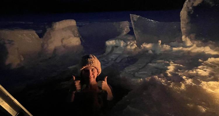 Persona disfrutando de un baño helado por la noche con bloques de hielo alrededor.
