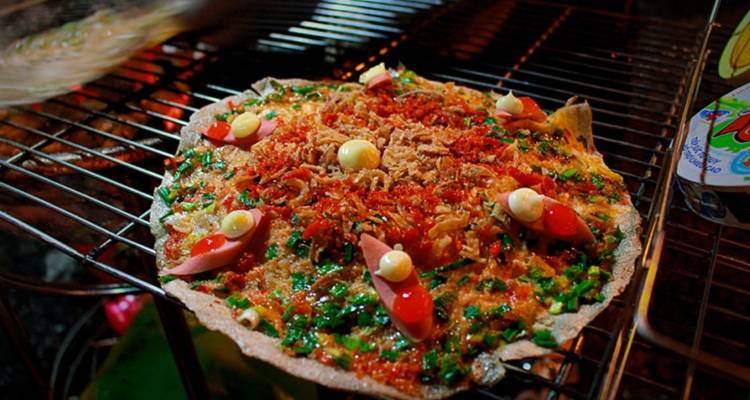 Vietnamesisches Straßenessen auf einem Grill, mit sichtbaren frischen Zutaten.