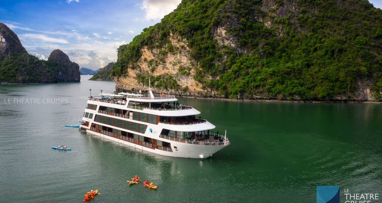 Un navire de croisière naviguant dans les eaux tropicales près de falaises calcaires.
