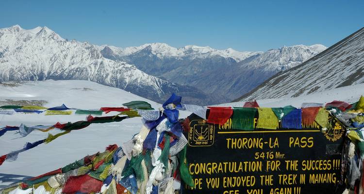 Thorong-La Pass bord behangen met gebedsviaggen tegen een breed panorama van besneeuwde bergen