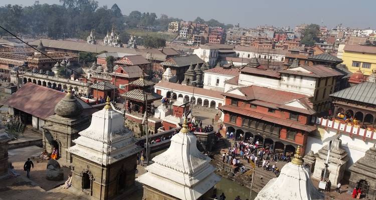 Erhöhter Blick auf den Pashupatinath-Tempelkomplex mit mehreren Schreinen und Menschenmengen entlang des Flussufers