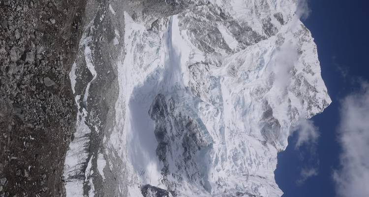 Towering icy mountain face and glacier under a clear sky