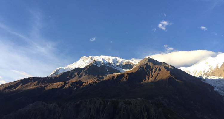 Sunlit Himalayan peaks with deep shadows on lower slopes under a vivid blue evening sky