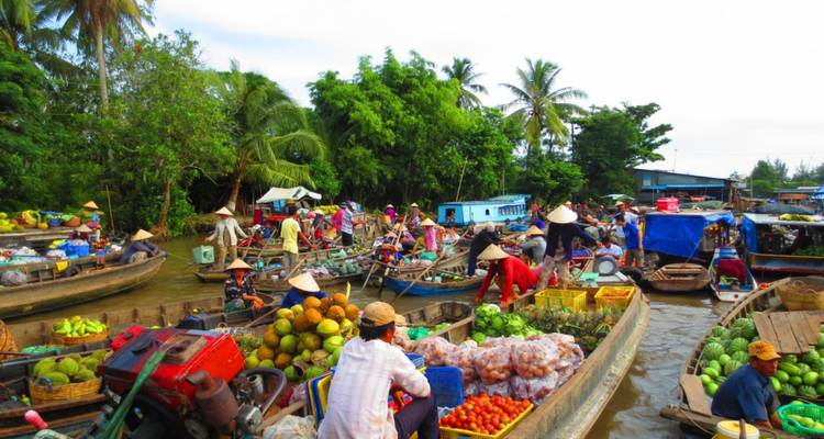 Busy floating market with vendors on boats selling goods.