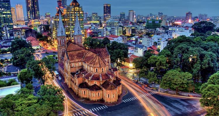 Vista de una catedral en una ciudad con rascacielos en el fondo.
