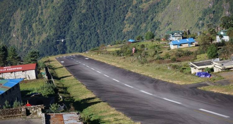 Narrow sloping runway of Lukla airport cutting through green Himalayan foothills