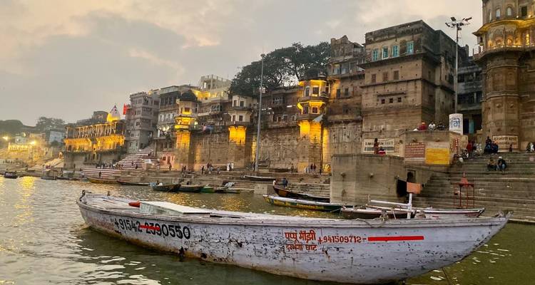 Vista de los ghats a lo largo del río con botes y edificios iluminados.
