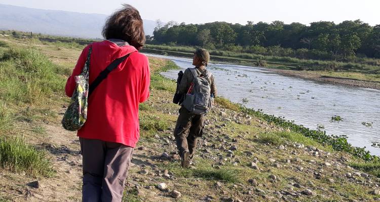 Two people walking beside a river in a natural setting.