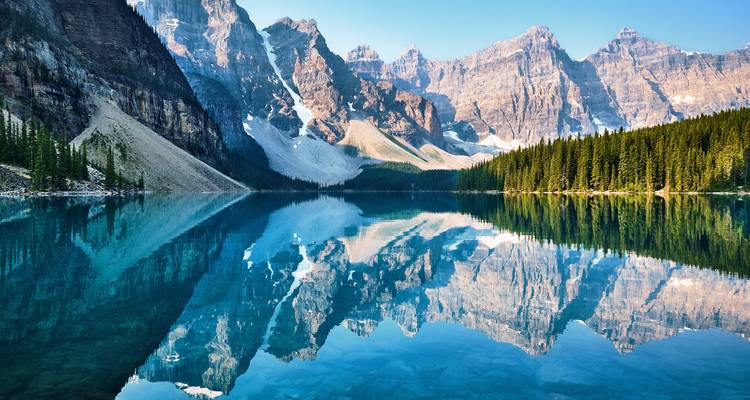 Mirror-like Moraine Lake perfectly reflects the dramatic Valley of the Ten Peaks at dawn.