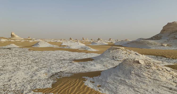 Vista paisajística del desierto con montículos arenosos y formaciones rocosas.