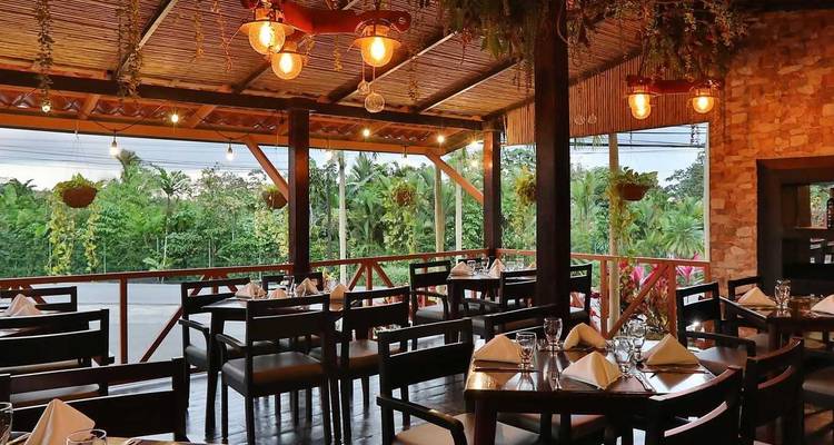 Restaurant à ciel ouvert accueillant avec des tables élégamment dressées et un éclairage chaleureux donnant sur la verdure.