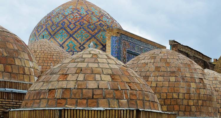 Serie de cúpulas de ladrillo en tonos tierra coronadas por una gran cúpula de mosaico azul en los bazares históricos de Bujará.