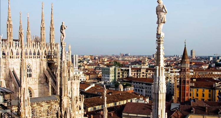Vista elevada desde las estatuas de la azotea de la Catedral de Milán que dominan el horizonte moderno de la ciudad.