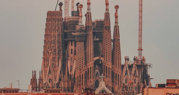 Vue au téléobjectif des flèches élancées de la Sagrada Família et des grues alors que la construction se poursuit au-dessus des toits de Barcelone.