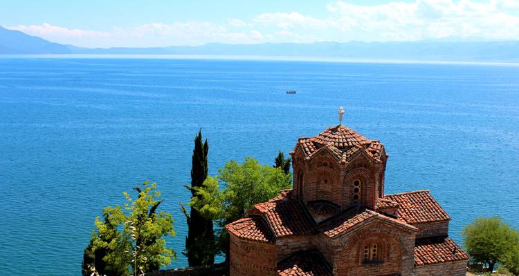 Church overlooking a large lake with mountains in the distance.