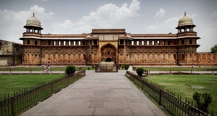 Fort van Agra met een tuin op de voorgrond en bewolkte luchten.